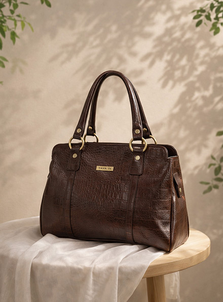 TANN IN brown leather top-handle tote in a sunlit setting